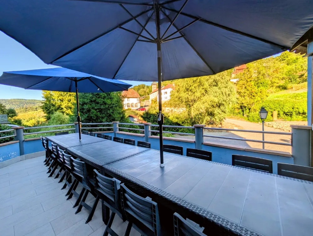 Grande terrasse ombragée du gîte LE 1880 avec parasols et tablée